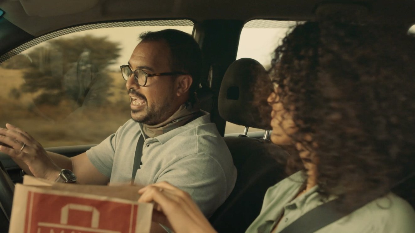 Couple driving in a car with wimpy takeaway bag