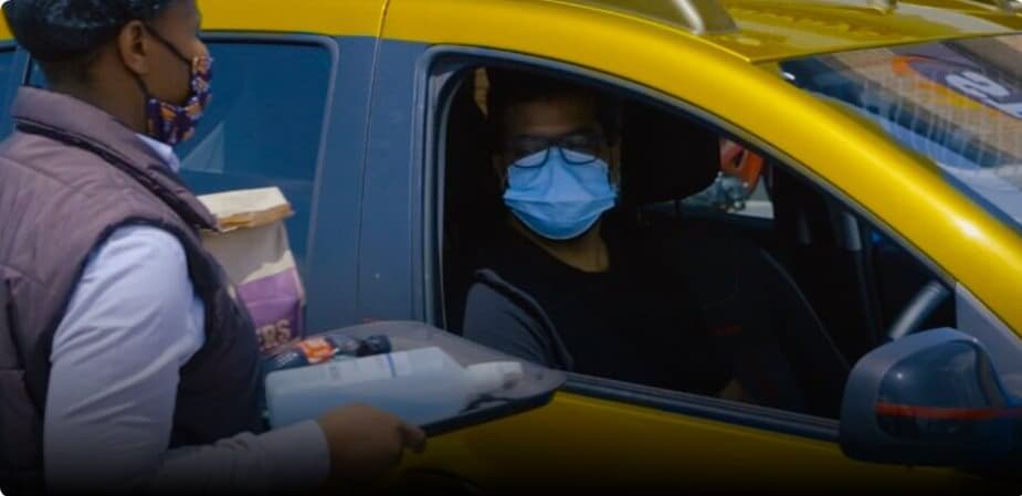 Person wearing a mask getting food delivered to their car