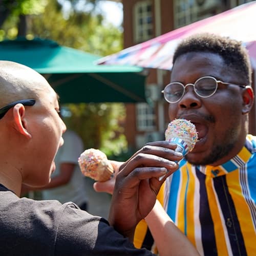 Two people eating ice cream together interlocking their arms