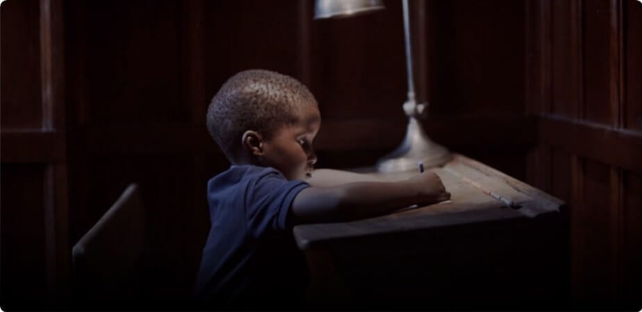 Child sitting at a desk writing on a piece of paper