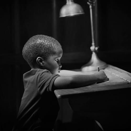 Child sitting at a desk writing on a piece of paper