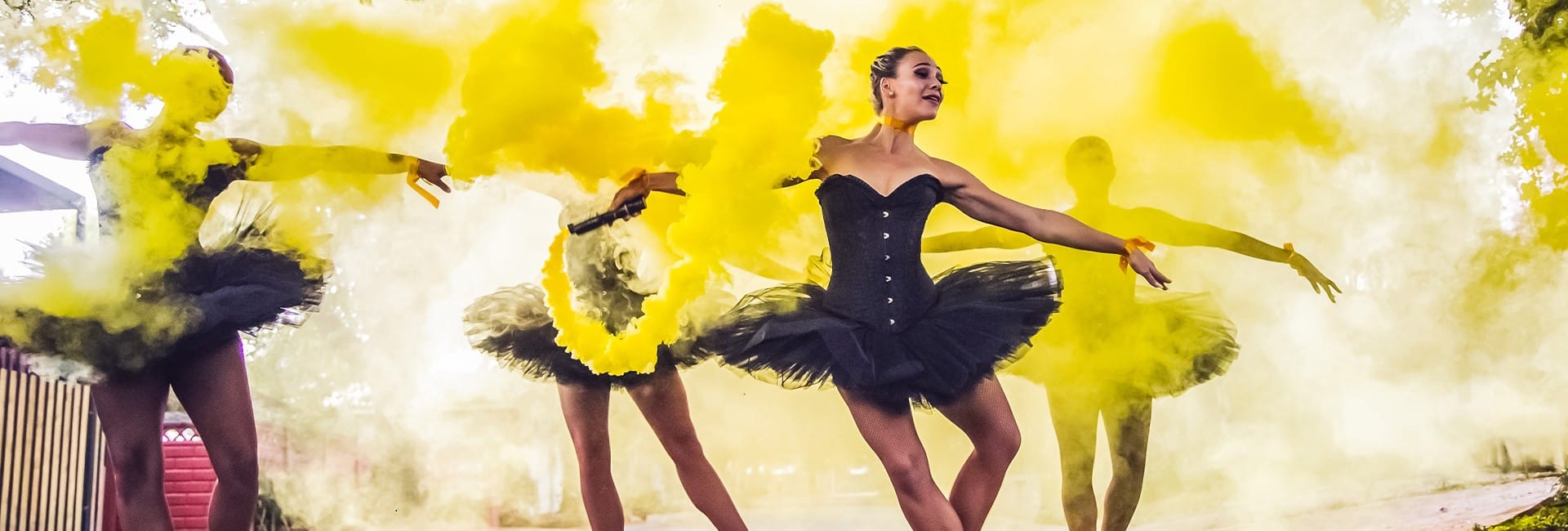 Ballerinas dancing around yellow smoke in black tutus