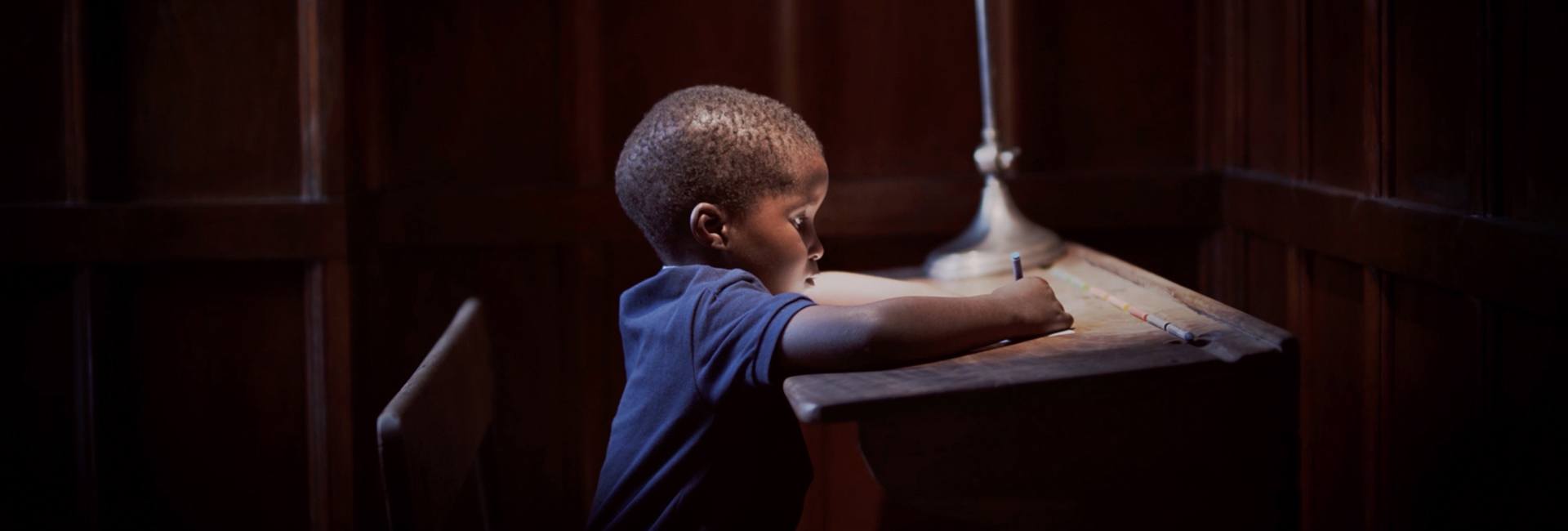 Child sitting at a desk writing on a piece of paper