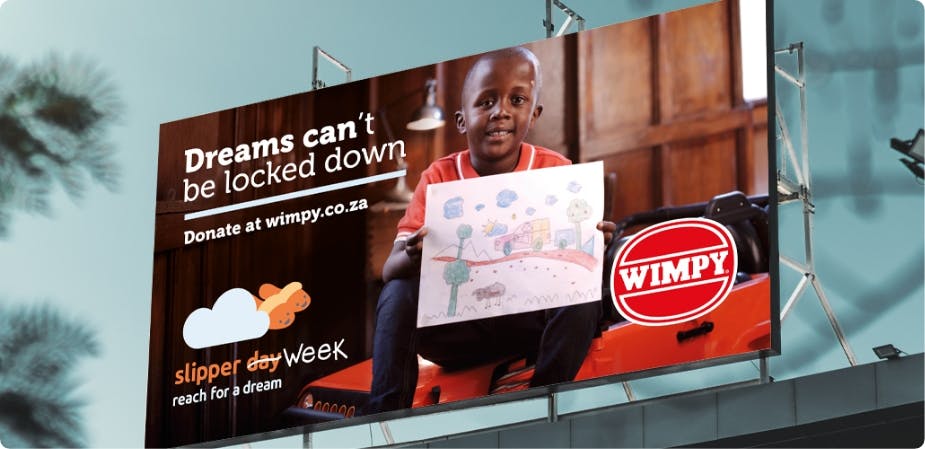 Reach for a dream billboard ad with boy holding his drawing
