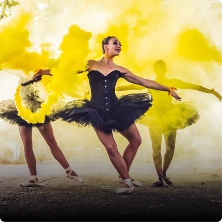 Ballarinas dressed in black dancing in yellow smoke